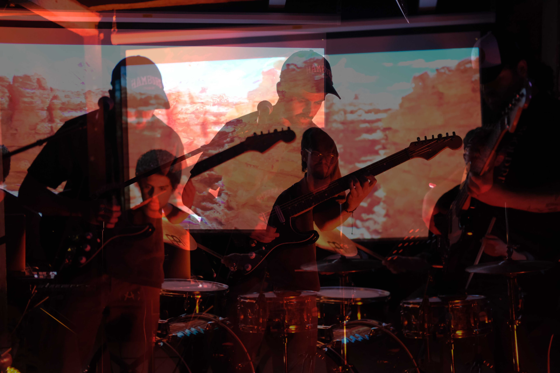 Layered long-exposure photo of guitarists and drums